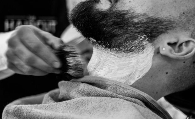 client getting a beard trim at a barbershop for men